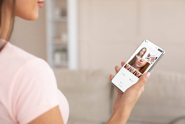 Blick über die Schulter einer Dame, die online auf dem Handy Kosmetika und verschiedene Lippenstiftfarben probiert, mit moderner Anwendung mit AR-Make-up-Simulation, kreativer Collage, selektivem Fokus