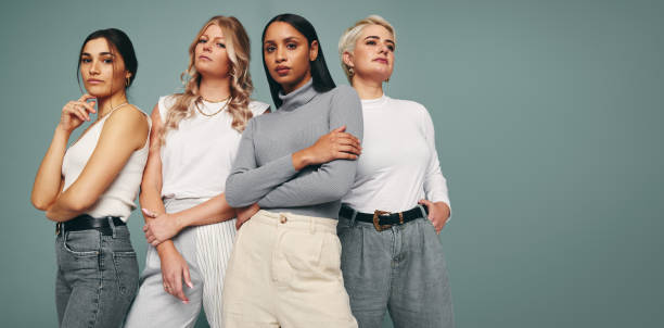 スタイルと自信。スタジオの背景に力を持った女性の多様なグループが一緒に立っている。スタジオに立つ自信に満ちた女性の友人。