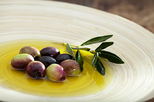 Rå oliven og olivenolie i træplade.