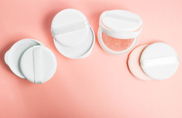 Refills of foundation and highlighter cushion on a pink background with sponge and puff