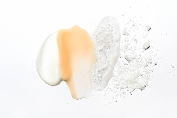 Mix of textures of cream, lotion, liquid gel and sea salt on a white background close-up. Mixed samples of beauty products. Smeared makeup, sprinkled salt, concealer and foundation smears